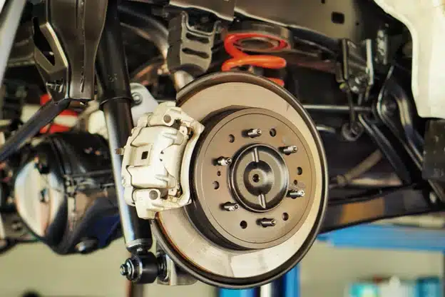 How fall weather affects your car’s braking system in Durango, CO with Firestone of Durango. Image of new car braking system while a car is on a lift in the shop.