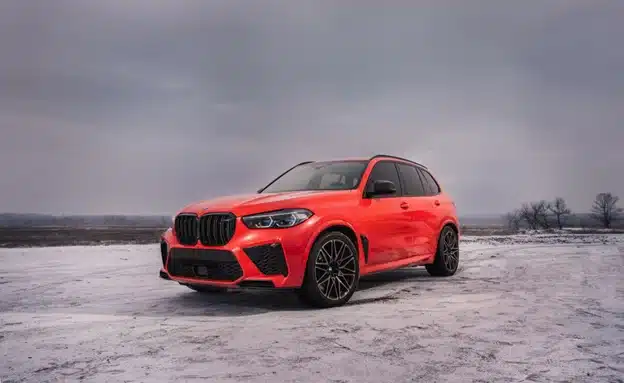 Prepping your car for winter in Durango, CO with Firestone of Durango. Image of red BMW SUV parked in a winter landscape.