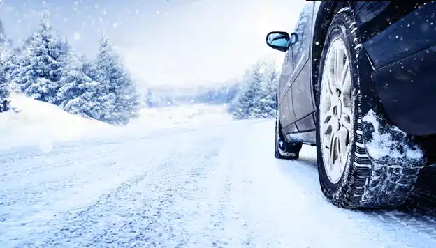 When should you change to winter tires in Durango, CO with Firestone of Durango? Image of a car with snow tires on it driving on a snow-covered winter road.