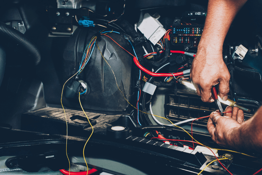 car electrical repair, auto repair in Durango, CO at Firestone of Durango. Hands working on car wiring with various colorful wires and components, highlighting intricate auto electrical repair.