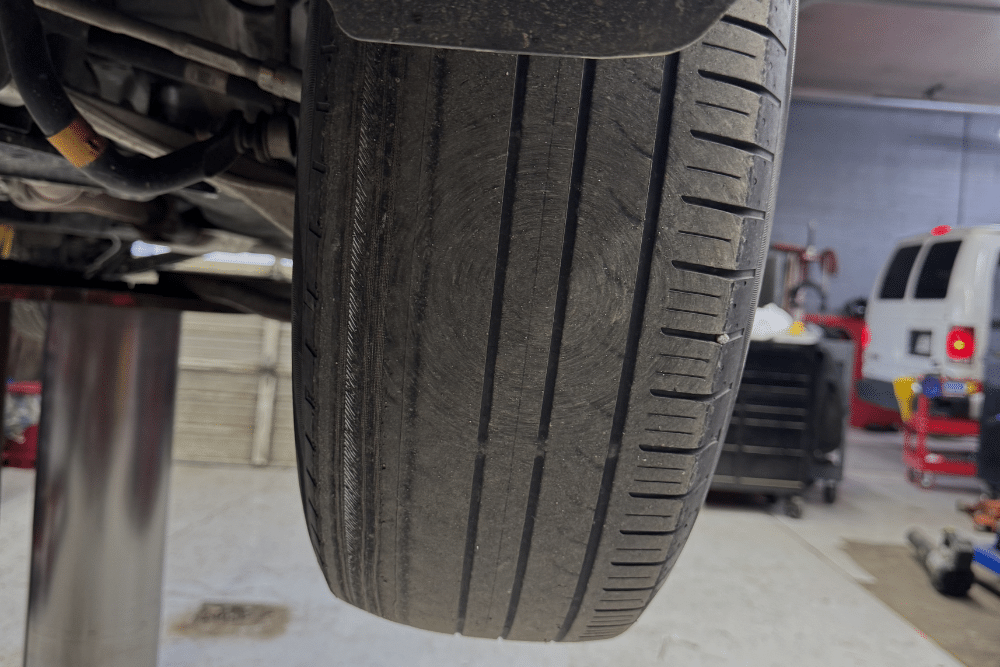 Tire Safety Service In Durango, CO At Firestone of Durango. Close-up view of a lifted vehicle tire during inspection