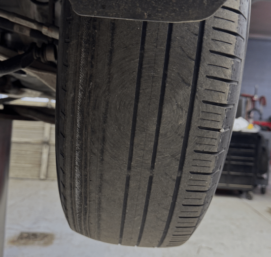 Tire Safety Service In Durango, CO At Firestone of Durango. Close-up view of a lifted vehicle tire during inspection