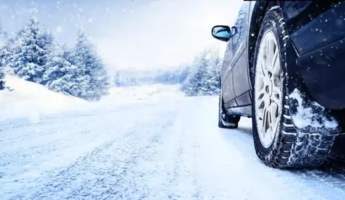 When should you change to winter tires in Durango, CO with Firestone of Durango? Image of a car with snow tires on it driving on a snow-covered winter road.